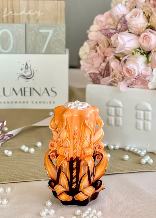 Hand-carved candle in black and orange with intricate layered design and glossy finish.