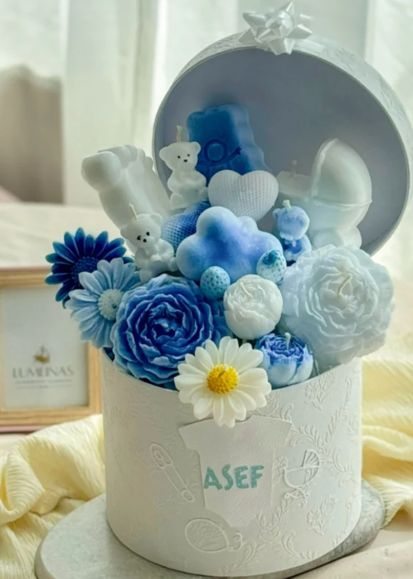 Handcrafted soy candles shaped as baby feet, teddy bear, miniature carriage, and flower candles inside an elegant keepsake box, perfect personalized newborn gift